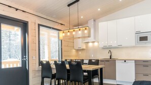 Een moderne keuken met een eethoek, witte kastjes en een groot raam.