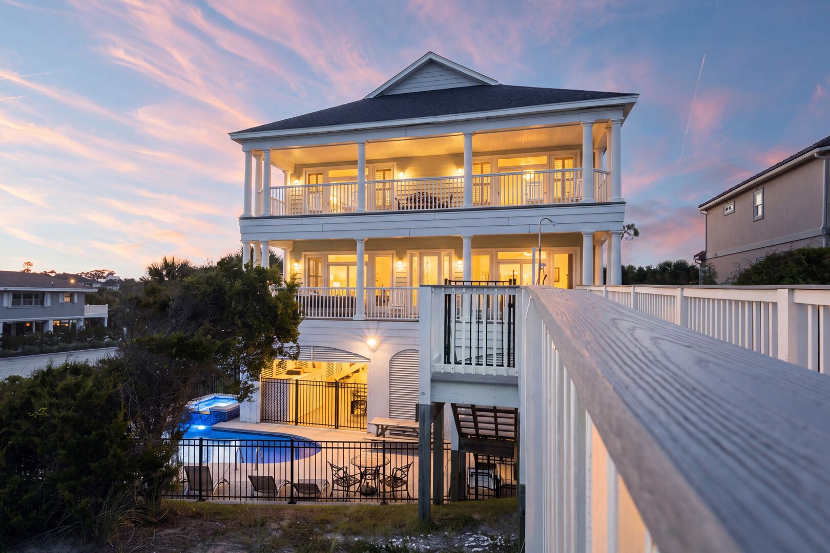 Una casa de dos pisos con balcón, piscina y terraza.