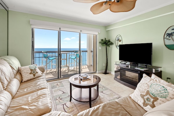 A living room with a sofa, a coffee table, a TV, and a balcony with a view of the sea. - Discover a top-tier beach getaway at SEA MARSH II 1003 (North Myrtle Beach)