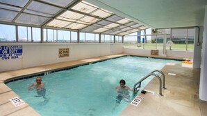 Ein Hallenbad mit klarem Wasser, Tiefenmarkierung von 1,5 Metern und Sicherheitsschildern, die auf flaches Wasser und Tauchverbot hinweisen.