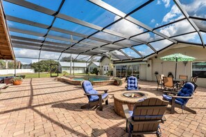 A covered patio area with outdoor furniture, a fire pit, and a pool.
