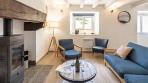 A cozy living room with a fireplace, a round table with a bottle and glasses, and a blue sofa.