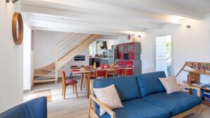 A modern living room with a blue sofa, wooden coffee table, and a staircase leading to a kitchen area.
