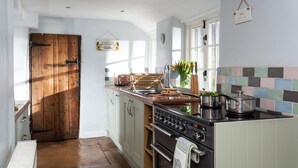 Une cuisine avec une porte en bois, un poêle et un pare-feu en carreaux.