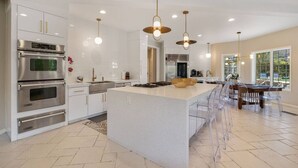 A modern kitchen with built-in appliances, a large island, and pendant lighting. - The Desert Castle with a Movie Theatre, golf, game room, sleeps 23 (Palm Desert)