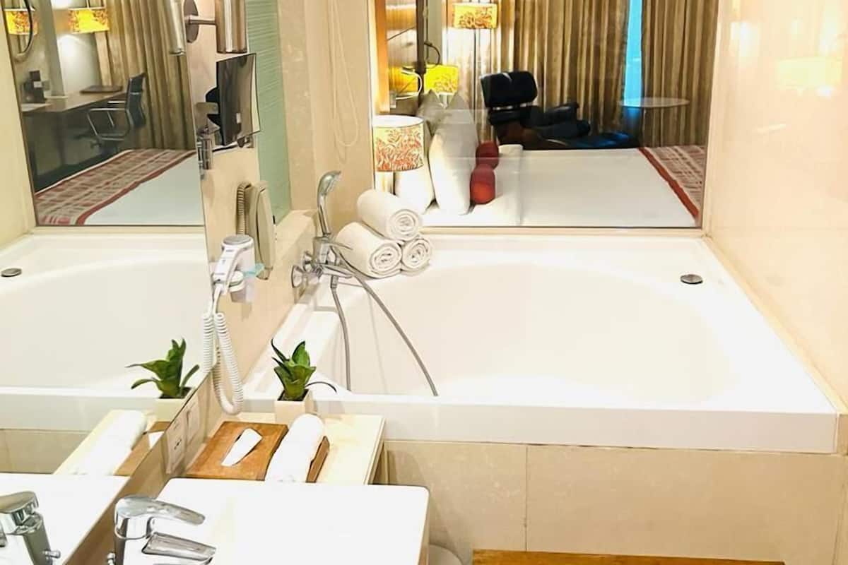A modern bathroom with two sinks, a large bathtub, and a wooden bench.