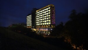 Un hotel de varios pisos con ventanas iluminadas y un llamativo elemento de luz púrpura en la fachada.