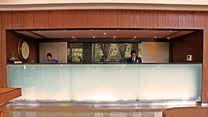 Mostrador de recepción con una recepcionista y un huésped sentado detrás.