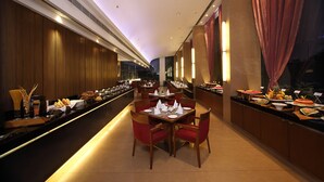 Un comedor de hotel con varias mesas, sillas y una barra de buffet.