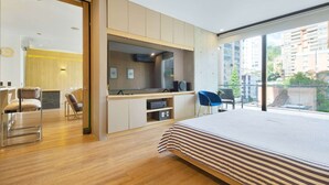 A modern bedroom with a large bed, a TV, and a desk area with a chair. - ONE BEDROOM HUGE BALCONY IN ENERGY ROOF POOL (Medellin)