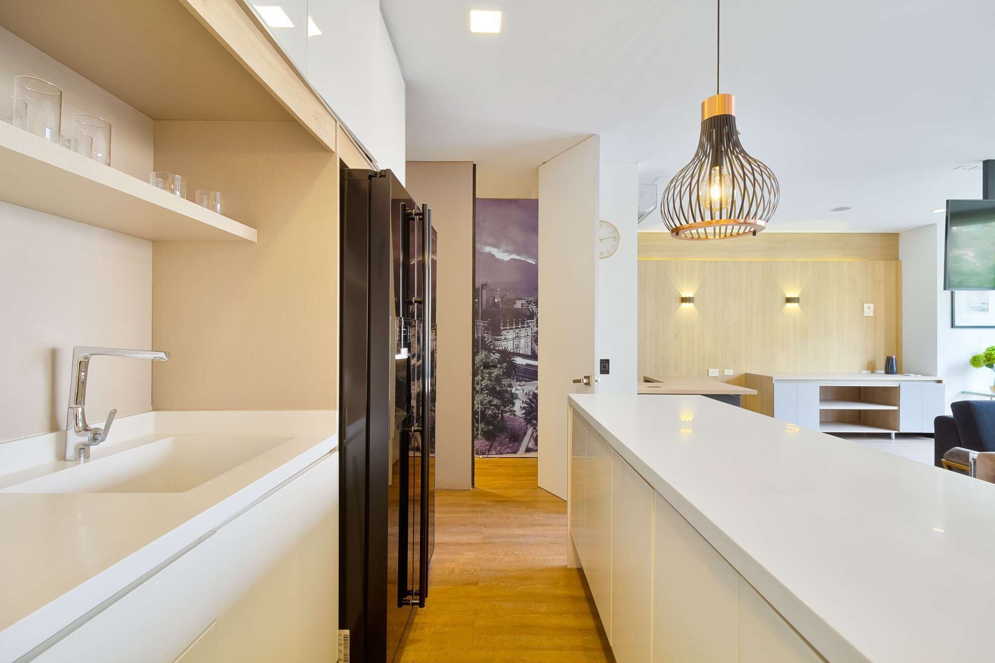 A modern kitchen with a white countertop, a black refrigerator, and a unique hanging light fixture.