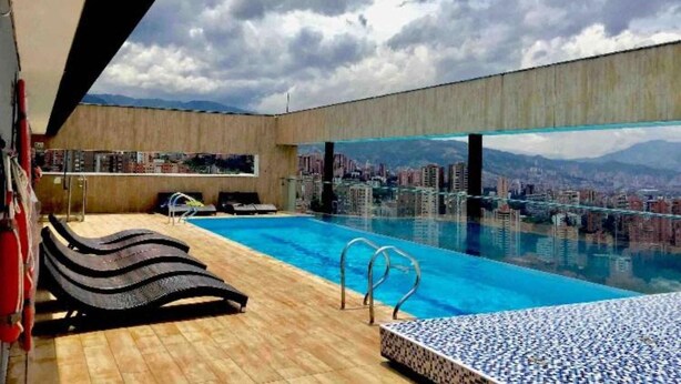 A rooftop infinity pool with lounge chairs and a city view. - ONE BEDROOM HUGE BALCONY IN ENERGY ROOF POOL (Medellin)