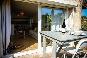 Una habitación con una mesa dispuesta para comer, una botella de vino y una copa sobre la mesa.