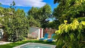 A swimming pool with a clear blue water surface, surrounded by a well-maintained lawn and various plants. - Gîte for two with private pool 20 minutes from Narbonne (Montséret)