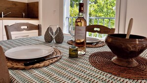 A dining table with a bottle of wine, two glasses, and a bowl with a spoon. - Gîte for two with private pool 20 minutes from Narbonne (Montséret)