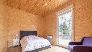 A bedroom with a bed, bedside tables, a chair, and a large window. - Wintersbourg Spa Retreat (Wintersbourg)