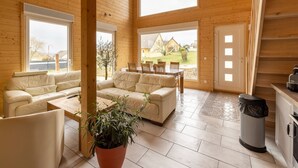 A spacious living area with a large window, a sofa set, a dining table, and a potted plant. - Wintersbourg Spa Retreat (Wintersbourg)