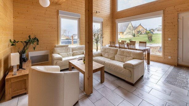 A spacious living area with a wooden ceiling, large windows, and a view of a residential area. - Wintersbourg Spa Retreat (Wintersbourg)