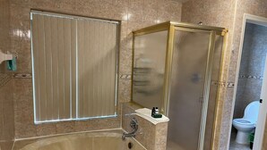 Ein Badezimmer mit Badewanne, Duschkabine, Toilette und Waschtisch mit Spiegel.