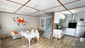 A modern living room with a dining area, kitchen, and staircase. - Portiragnes Group Stay with 2 pools (Portiragnes)