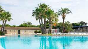 Une piscine avec des chaises longues et des palmiers.