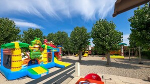 Un terrain de jeux extérieur avec des structures gonflables et, en arrière-plan, un beffroi.