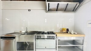 Een keuken met roestvrijstalen apparatuur, een houten aanrecht en een betegelde spatwand.