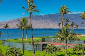 Un court de tennis offrant une vue sur l’océan et les montagnes.