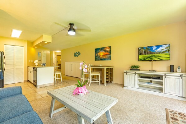 A compact living space with a kitchenette, dining area, and a TV mounted on the wall.