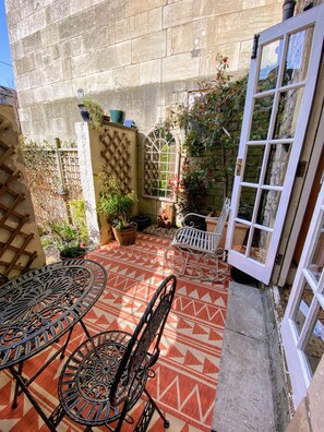 A patio with patterned flooring, metal furniture, a lattice wall, and a door with glass panels.