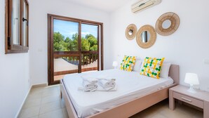 Un dormitorio con cama, mesita de noche, ventana y vistas al verdor.