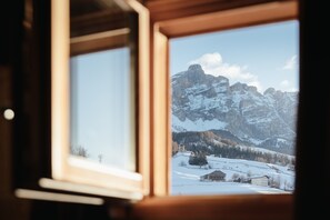 Una ventana con vistas a montañas nevadas y un edificio pequeño.