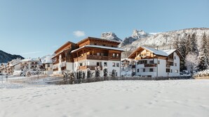 Un complejo turístico en la montaña cubierto de nieve, con edificios de madera, pistas de esquí y un cielo despejado.