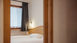 Una habitación de hotel con cama, ventana con cortinas y lámpara de pared.
