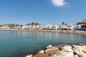 A coastal town with buildings along the shore, a rocky beach, and clear blue water. - Beach Apartment in Malaga with Sea View, Terrace & Wi-Fi (Málaga)