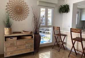 A modern kitchen with a large window, wicker furniture, and a decorative wall piece.
