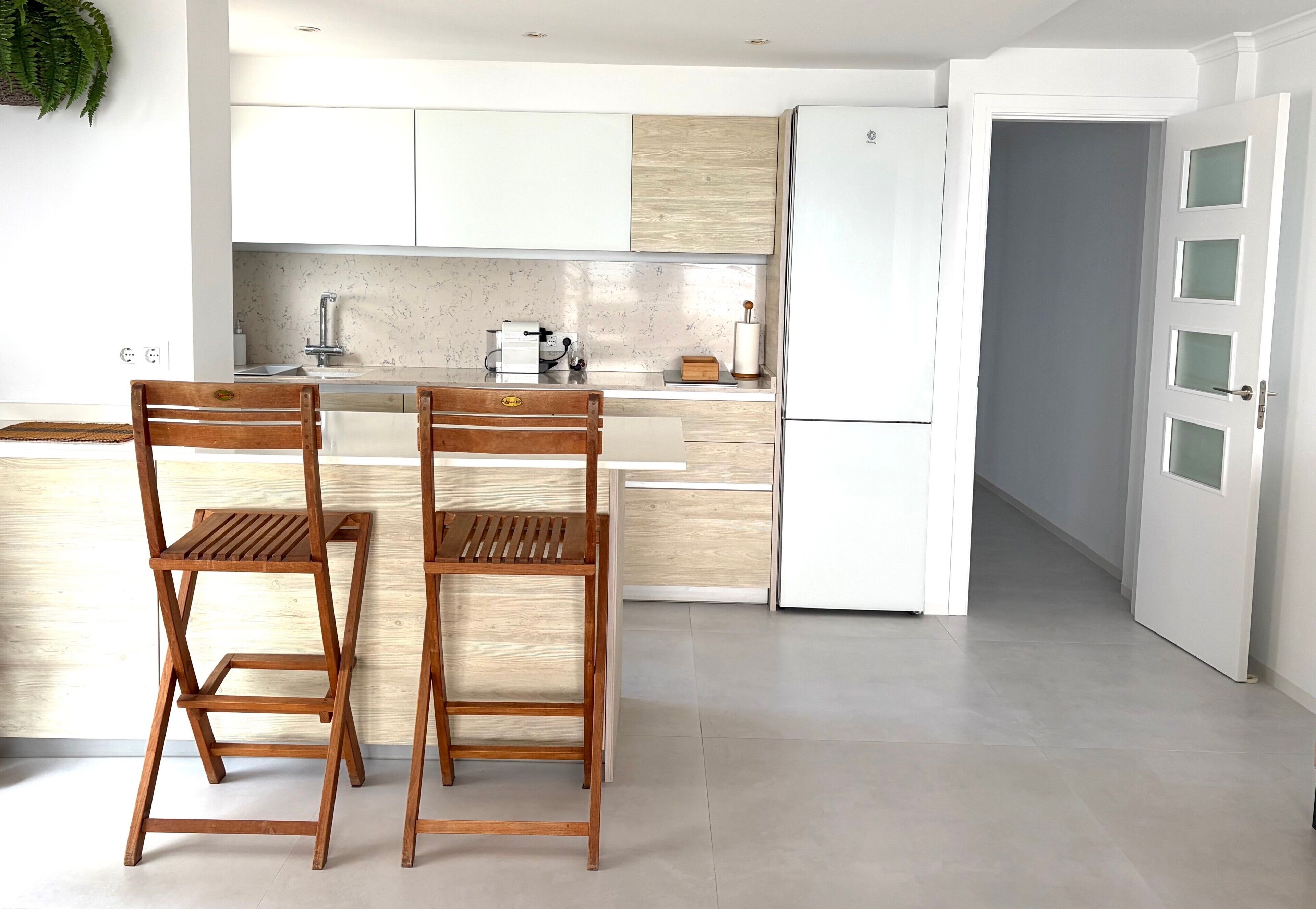 A modern kitchen with white cabinets, a marble backsplash, and a built-in refrigerator.