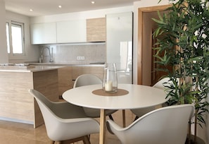 Una cocina moderna con una isla central, sillas blancas y una mesa de comedor.