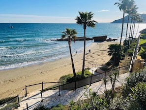 Une plage avec un escalier en pierre descendant jusqu’au rivage, des palmiers et une vue dégagée sur l’océan.