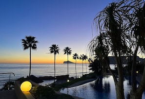 Une vue sur le coucher de soleil, avec des palmiers et une piscine.