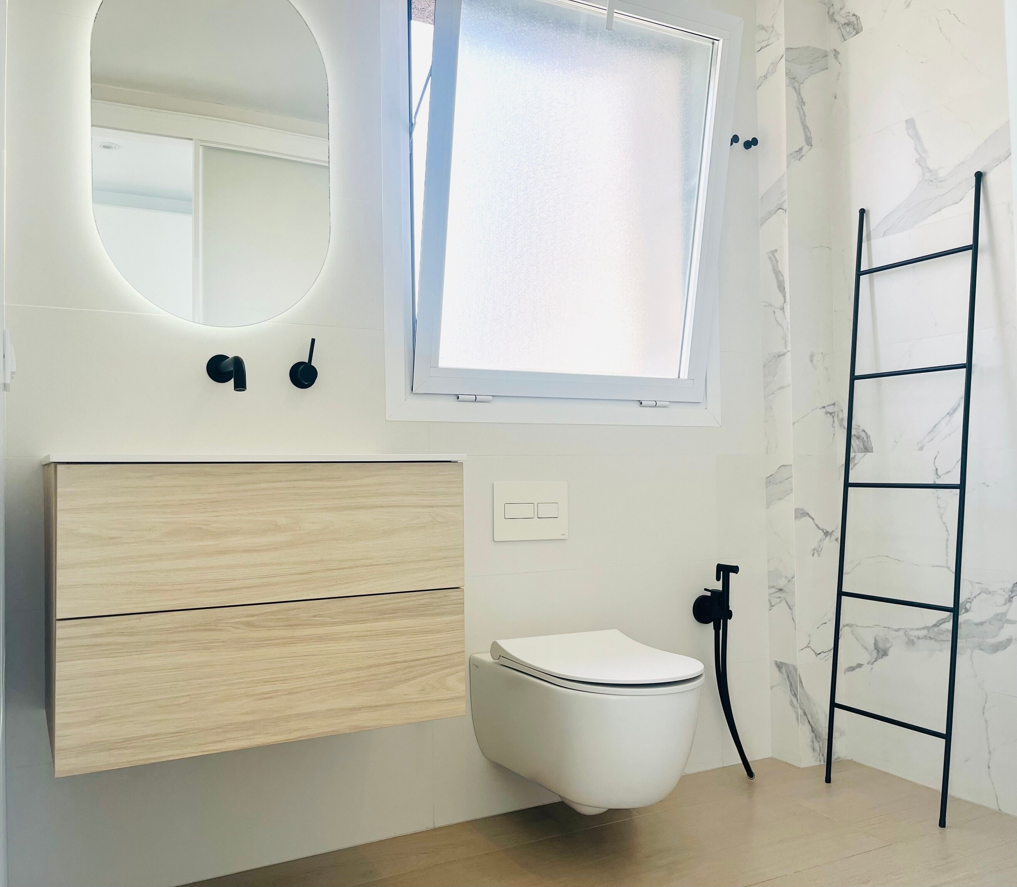 Un baño moderno con inodoro, lavamanos, tocador y ventana.