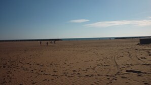 A wide sandy beach with footprints and a few people walking. - Appartement en sous-sol.Jardin privé. Situé dans un village des montagnes noires (Labastide-Rouairoux)