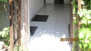 A corridor with tiled flooring, framed pictures on the walls, and a door leading to another room. - Appartement en sous-sol.Jardin privé. Situé dans un village des montagnes noires (Labastide-Rouairoux)