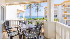 Un balcone con tavolo e sedie, con vista su una spiaggia e palme.