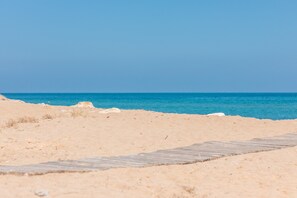 Une plage de sable avec une promenade en bois qui mène à l’eau.