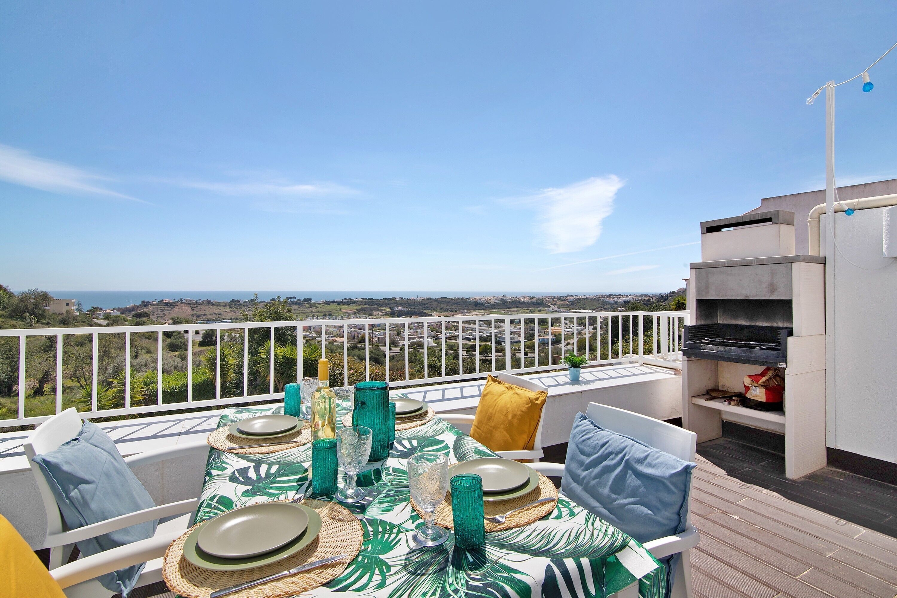 Eine Terrasse mit Esstisch, Grill und Blick auf die Landschaft.