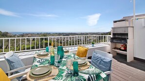 Una terrazza con tavolo apparecchiato per mangiare, un barbecue e vista sul paesaggio.