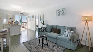 Un soggiorno moderno con un divano, un tavolino, una lampada e un'area cucina sullo sfondo.