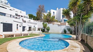 Una piscina con un design circolare, circondata da un solarium in pietra.