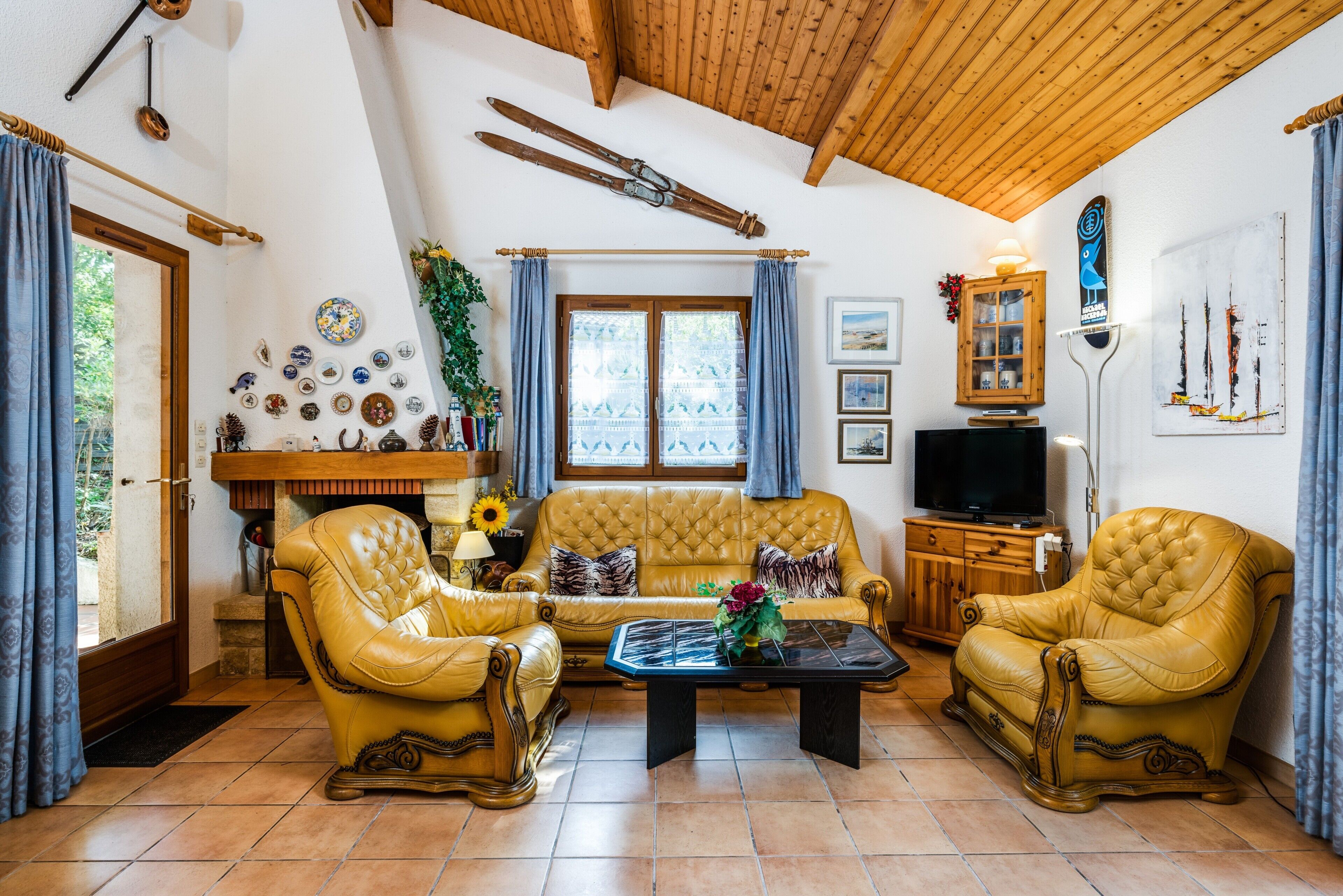 Una sala acogedora con un sofá, dos sillones, una mesa de centro y una televisión.